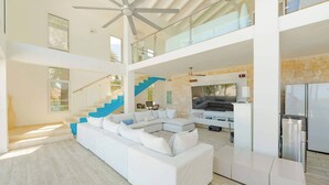 A spacious living area with a large white sectional sofa, a staircase, and a kitchen area. - 5BR Hispaniola Villa in Sosua (Sosúa)