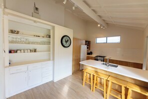 Eine moderne Küche mit weißen Schränken, einer Holzbar und einer Wanduhr.