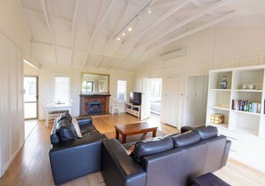 Ein geräumiges Wohnzimmer mit Kamin, Ledersofas, einem Holztisch und einem Bücherregal.
