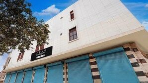 Ein Gebäude mit einem Schild, das 'Collection 5 commercial services' zeigt, blauen Fensterläden und einem strahlend blauen Himmel.
