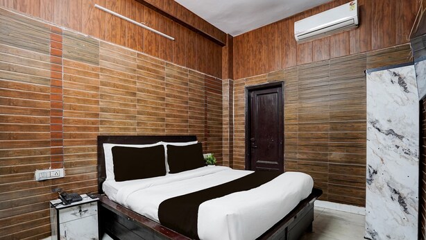 Ein Schlafzimmer mit einer Holzwand, einem Bett mit weißer Bettwäsche, einem Nachttisch und einem Kleiderschrank.