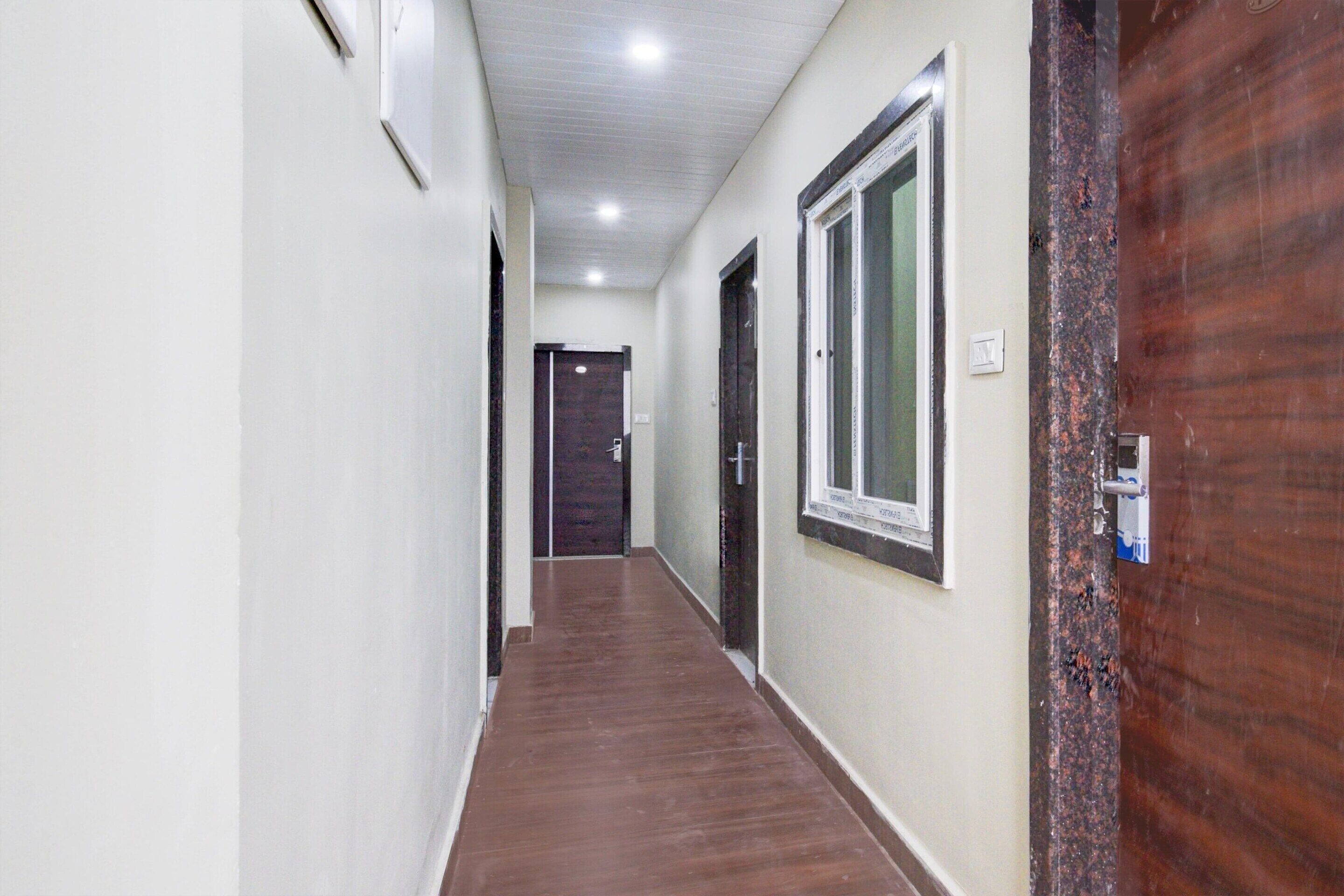 A hallway with a wooden floor, white walls, and a door at the end.