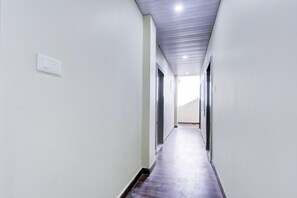 Corredor com paredes brancas, piso de madeira e teto com iluminação embutida.