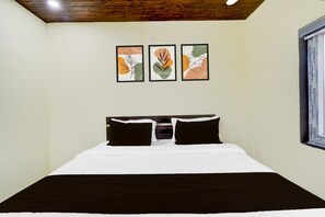 A bedroom with a bed, two pillows, and three framed artworks on the wall. - Suite Hotel Rans (Hyderabad)