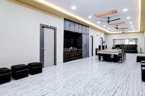 A modern hotel room with a large dining table, built-in cabinets, and ceiling fans.