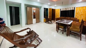 Un amplio espacio de estar con una mesa de comedor, sillas, un sillón mecedora y un armario.