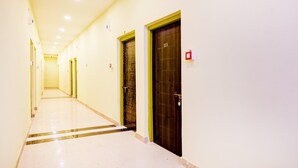 A long, narrow hallway with doors on both sides, a tiled floor, and ceiling lights. - Deluxe Howrah Tanima Villa (Howrah)