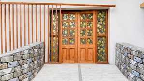 A wooden door with glass panels, a stone wall, and a metal gate. - Deluxe Howrah Tanima Villa (Howrah)