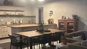 A modern kitchen with a dining area, wooden cabinets, and a built-in island. - Ingonyama Rest (Marloth Park)