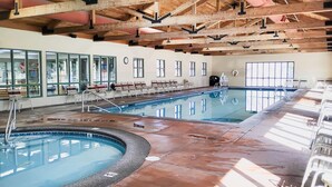 An indoor swimming pool with a tiled edge, a wooden ceiling, and a row of chairs along the poolside. - Elegant Fairway Frontage Retreat-Eagle Crest Resort 3BD 2.5BA Centrally Located (Redmond)