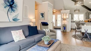 A modern living room with a grey sofa, a coffee table with a plant, and a large floral painting on the wall. - Elegant Fairway Frontage Retreat-Eagle Crest Resort 3BD 2.5BA Centrally Located (Redmond)