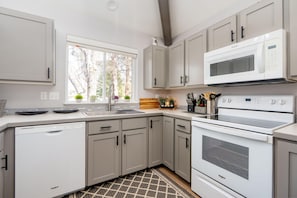A modern kitchen with built-in appliances, a dishwasher, and a window providing natural light.