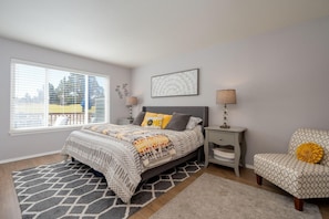 A bedroom with a bed, bedside tables, a chair, and a window.