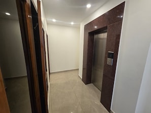 Un couloir avec un ascenseur en marbre et une porte dotĂ©e dâune poignĂ©e.