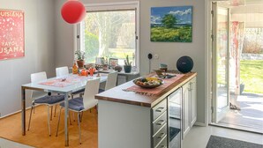 Moderni keittiö, jossa on ruokailutila, punainen riippuvalaisin ja taulu seinällä.
