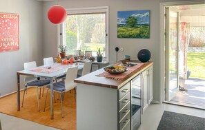 Ett modernt kök med en matplats, en röd hänglampa och en tavla på väggen.