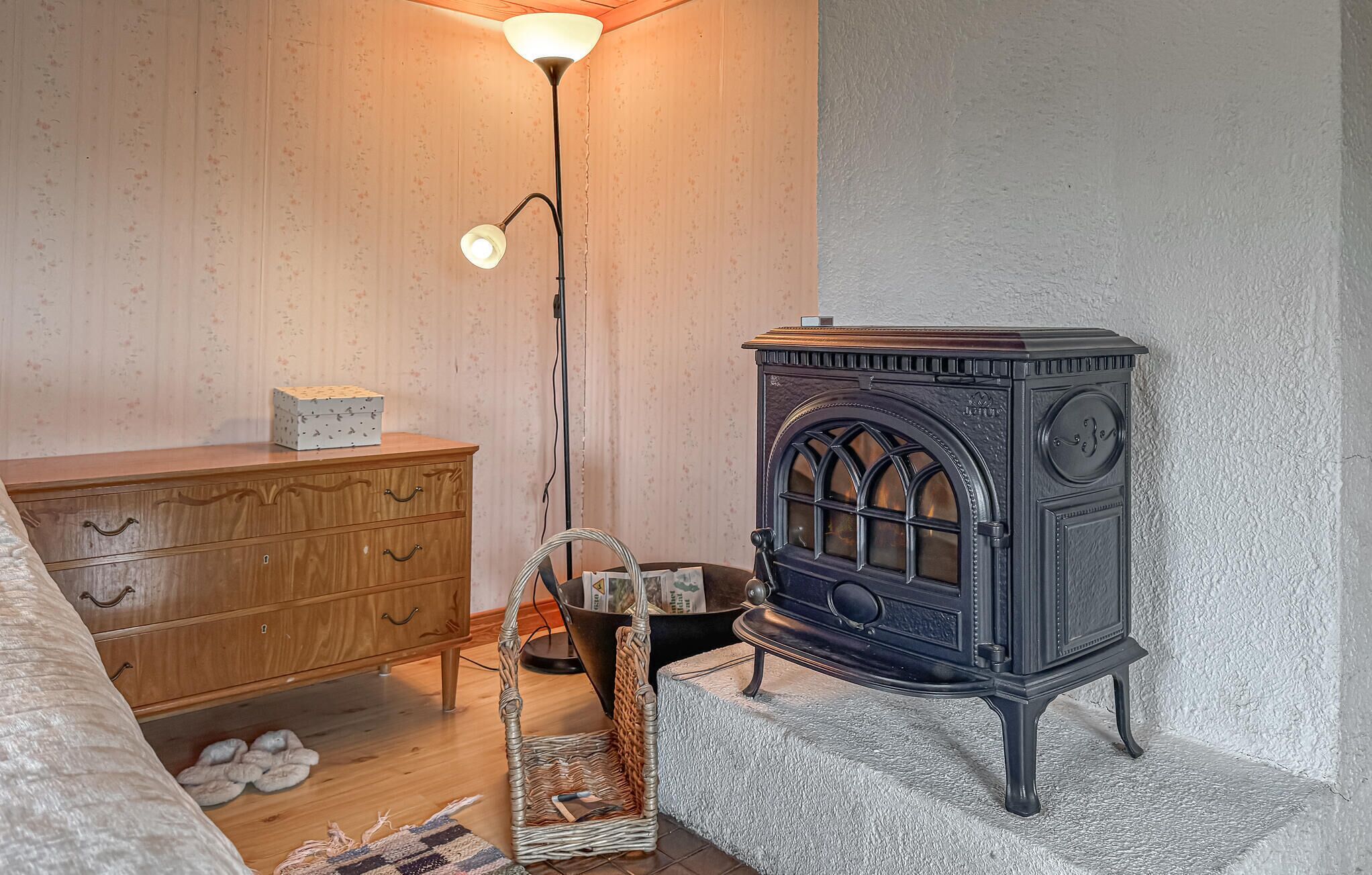 A room with a vintage stove, wooden dresser, and a floor lamp.