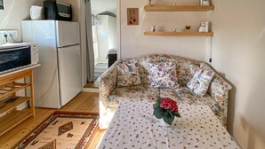 Un espacio habitable compacto con sofá, una mesa pequeña, refrigerador y televisor.