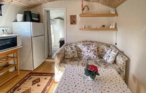 Un espacio habitable compacto con sofá, una mesa pequeña, refrigerador y televisor.