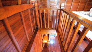 Un interior de madera con una escalera que baja a un nivel inferior.