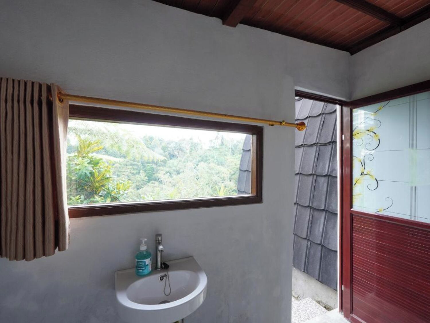 A bathroom with a window, a sink, and a shower area.