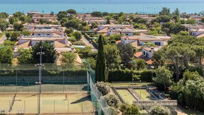 Ein Tennisplatz, umgeben von Wohnhäusern mit Blick auf das Meer.