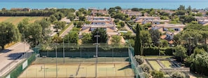 Ein Tennisplatz, umgeben von Wohnhäusern mit Blick auf das Meer.