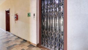 A hallway with a fire extinguisher, a number 2 sign, and a metal gate. - Deluxealpine Glow Pinnacle (Hyderabad)