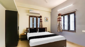 A bedroom with a bed, an air conditioning unit, a ceiling fan, a window with curtains, and a wall-mounted picture. - Deluxealpine Glow Pinnacle (Hyderabad)