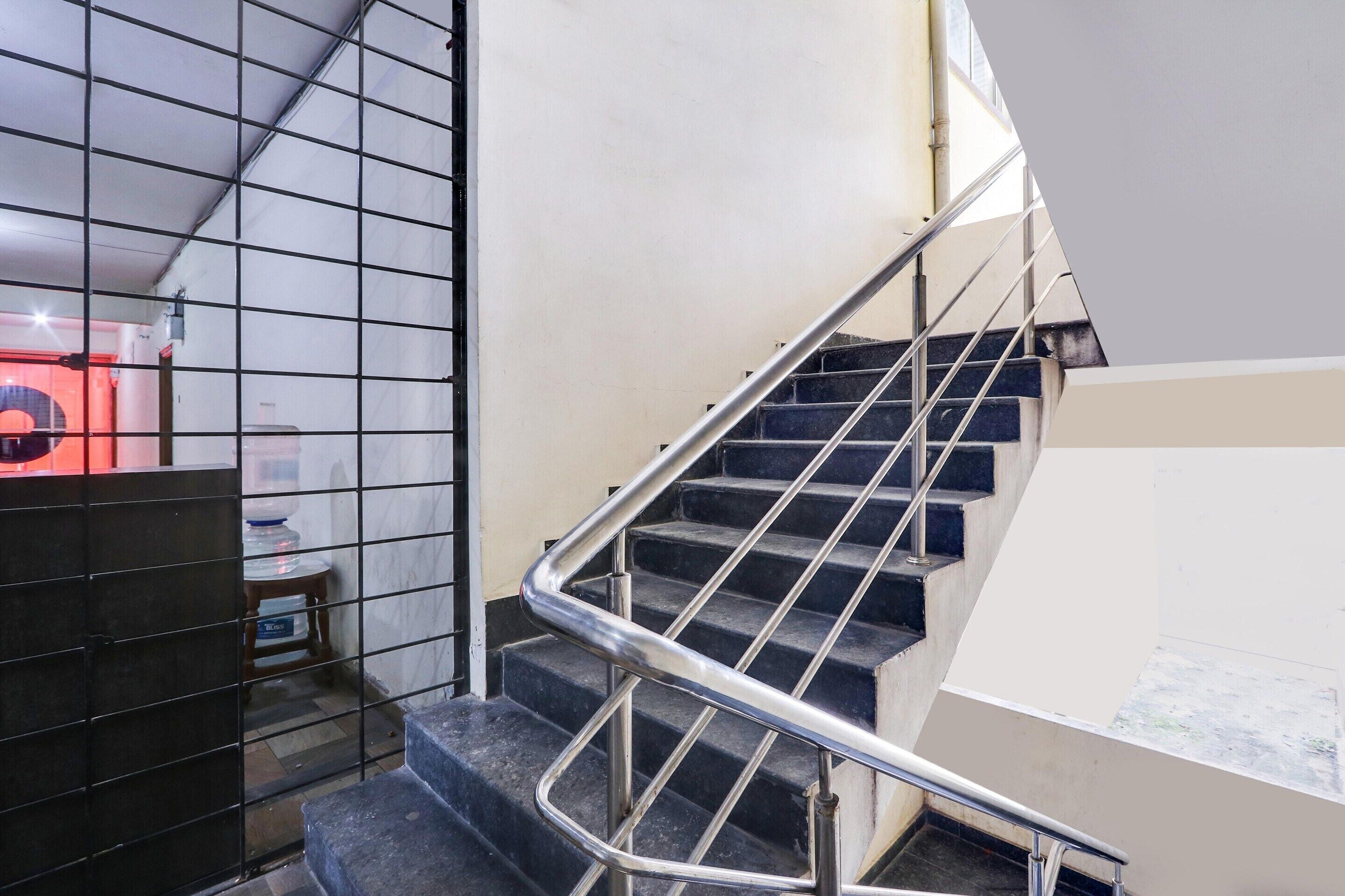 Un escalier avec des rampes en métal, un sol carrelé et un mur orné d’un motif en réseau.