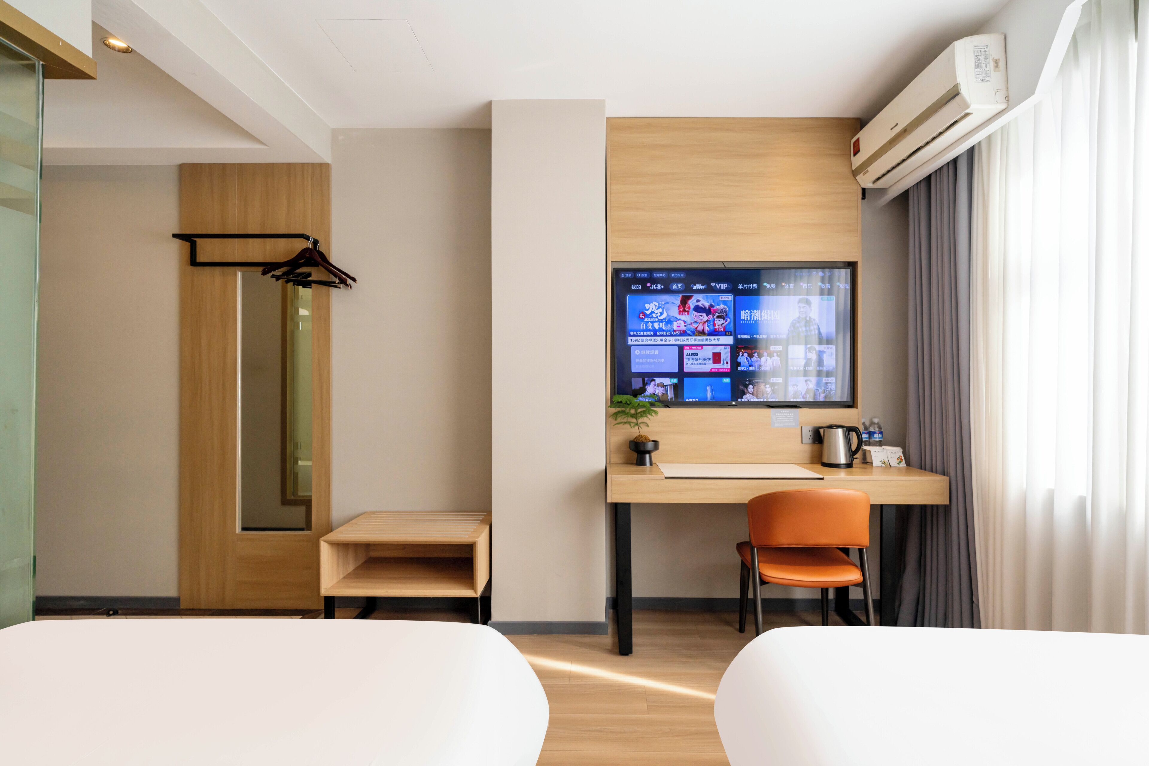 A hotel room with a wooden desk, a television, a chair, and a bed.