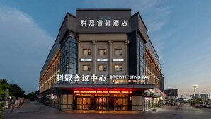 Un hotel con diseño arquitectónico moderno, que destaca por una entrada principal con puertas de vidrio y un cartel que indica que es el Crown Crystal Conference Center.