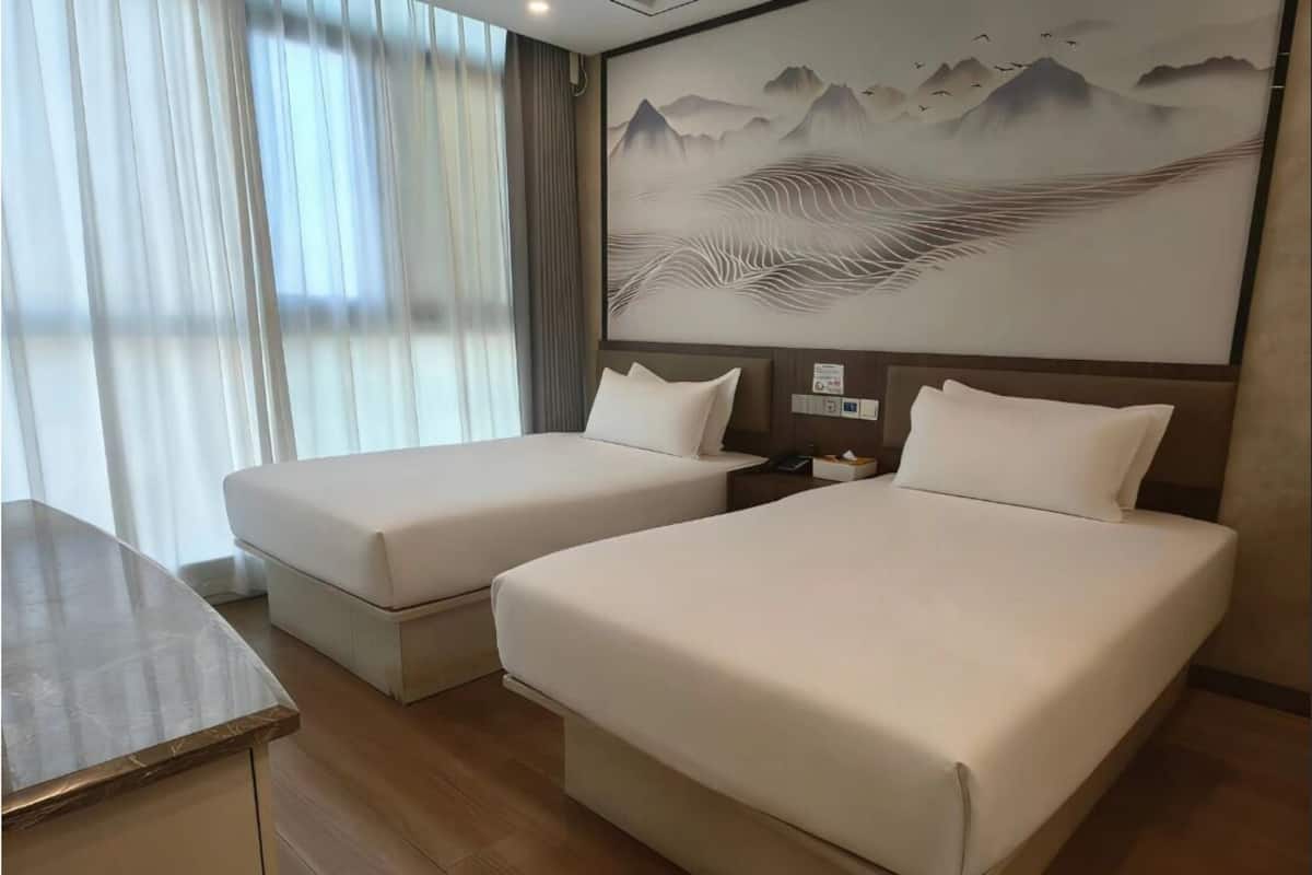 Habitación de hotel con dos camas, un escritorio y un cuadro grande en la pared.