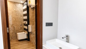 Ein modernes Badezimmer mit einer Duschkabine aus Marmor, einem weißen Waschbecken und Holzboden.