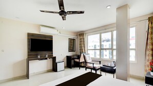 Een hotelkamer met een bed, een bureau, een stoel, een televisie en een raam.