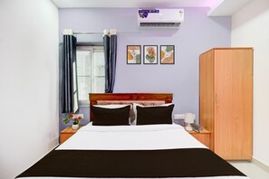 A bedroom with a bed, a wardrobe, a nightstand, a window with curtains, and wall art. - Single Room Hotel Lanco Hills (Hyderabad)
