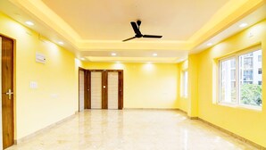 A spacious hallway with a ceiling fan, a large window, and a door leading to another room. - Deluxe Rosedale Reliance Guest House (Barasat)