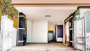 A hallway with a checkered floor, white gates on either side, and a staircase leading to an upper level.