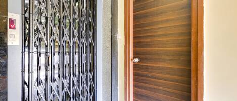 A door with a metal security gate, a wooden door, and a small step leading to the entrance.