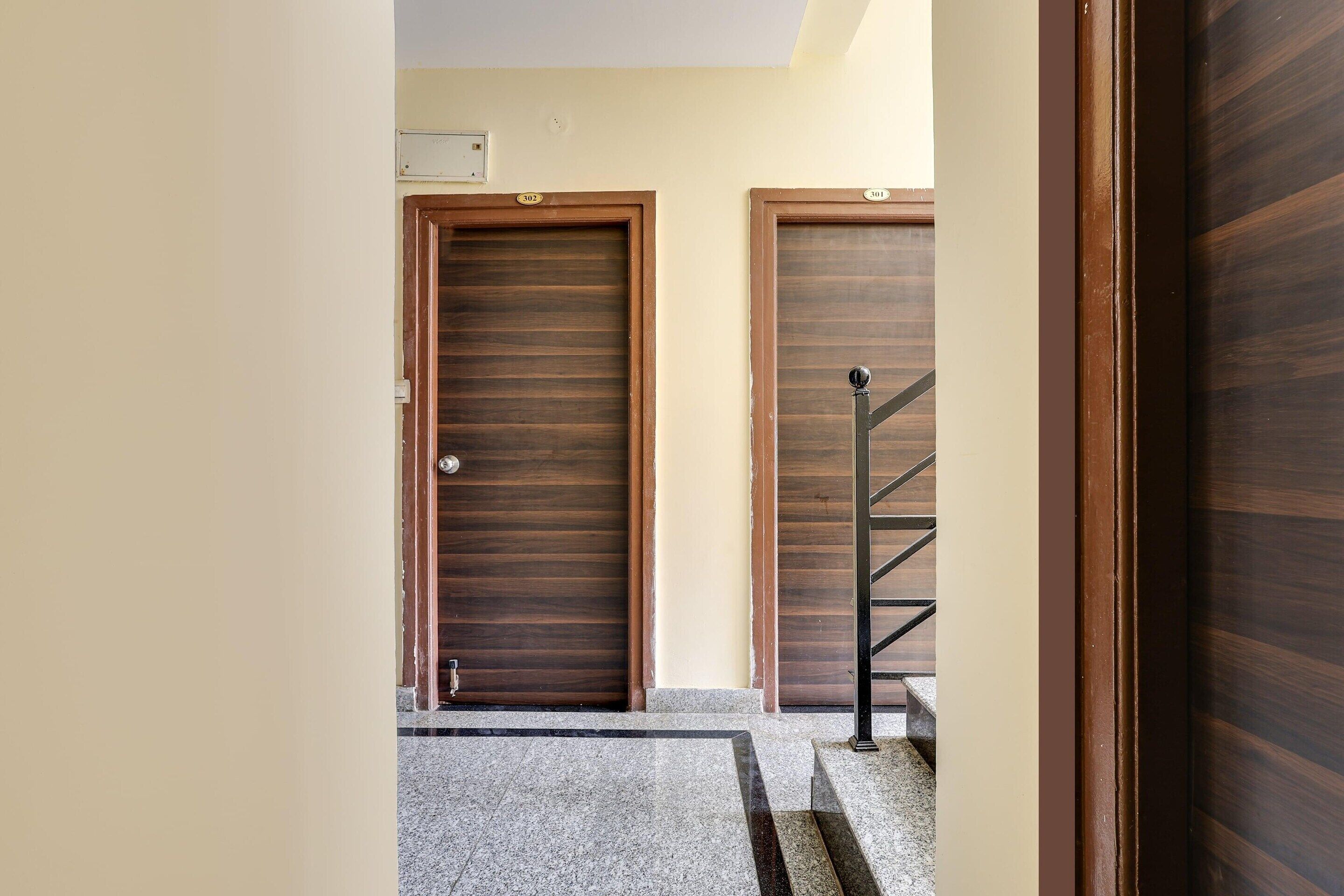 A hallway with two wooden doors, a metal staircase, and a tiled floor.