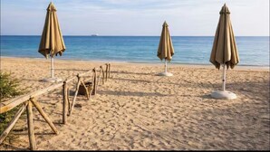 Ein Strand mit drei Sonnenschirmen und einem Holzzaun.