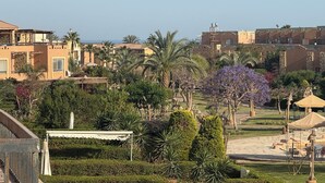 Ein angelegter Garten mit einem Gartenpavillon, Palmen und Blick auf traditionelle Gebäude im Hintergrund.