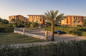 A residential complex with multiple two-story buildings, a gated entrance, and a palm tree.