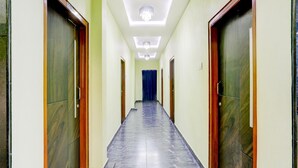 A hallway with a tiled floor, wooden doors, and a blue curtain at the end.
