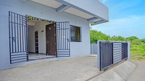 A modern building with a concrete entrance, a metal gate, and a window with horizontal bars.