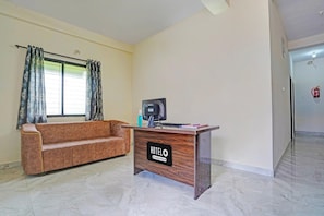 Uma área de recepção de hotel com um sofá, uma mesa com um computador e uma placa com a inscrição 'HOTEL O'.