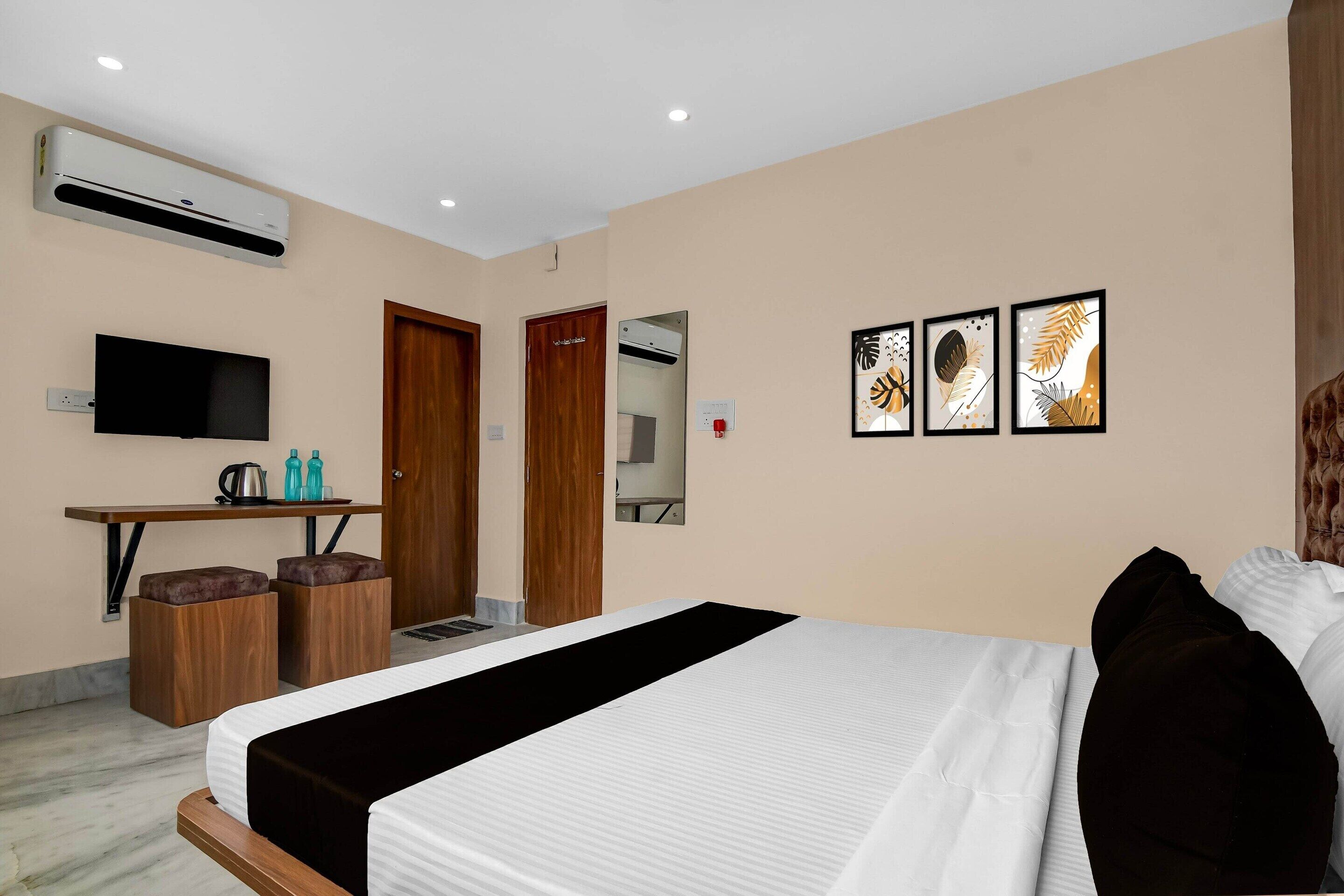 Une chambre d’hôtel comprenant un lit, un bureau avec une chaise, une télévision et des œuvres d’art accrochées au mur.