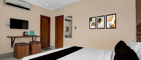 Une chambre d’hôtel comprenant un lit, un bureau avec une chaise, une télévision et des œuvres d’art accrochées au mur.