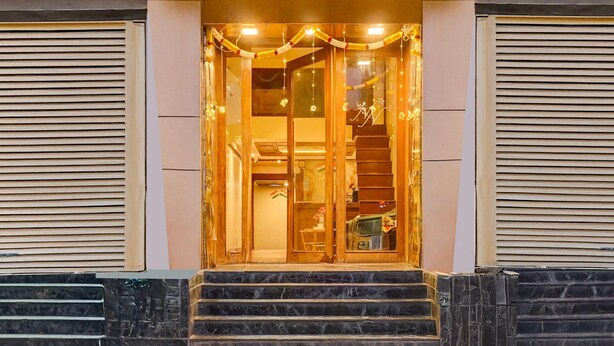 A building entrance with a staircase leading up to a door, a set of stairs on either side, and a decorative string of lights above the door. - Deluxe Viman Nagar Downtown Cilantro (Pune)
