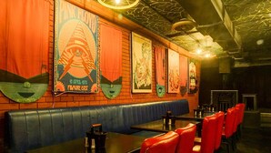 A restaurant interior with booths, red chairs, and a brick wall with posters. - Deluxe Viman Nagar Downtown Cilantro (Pune)